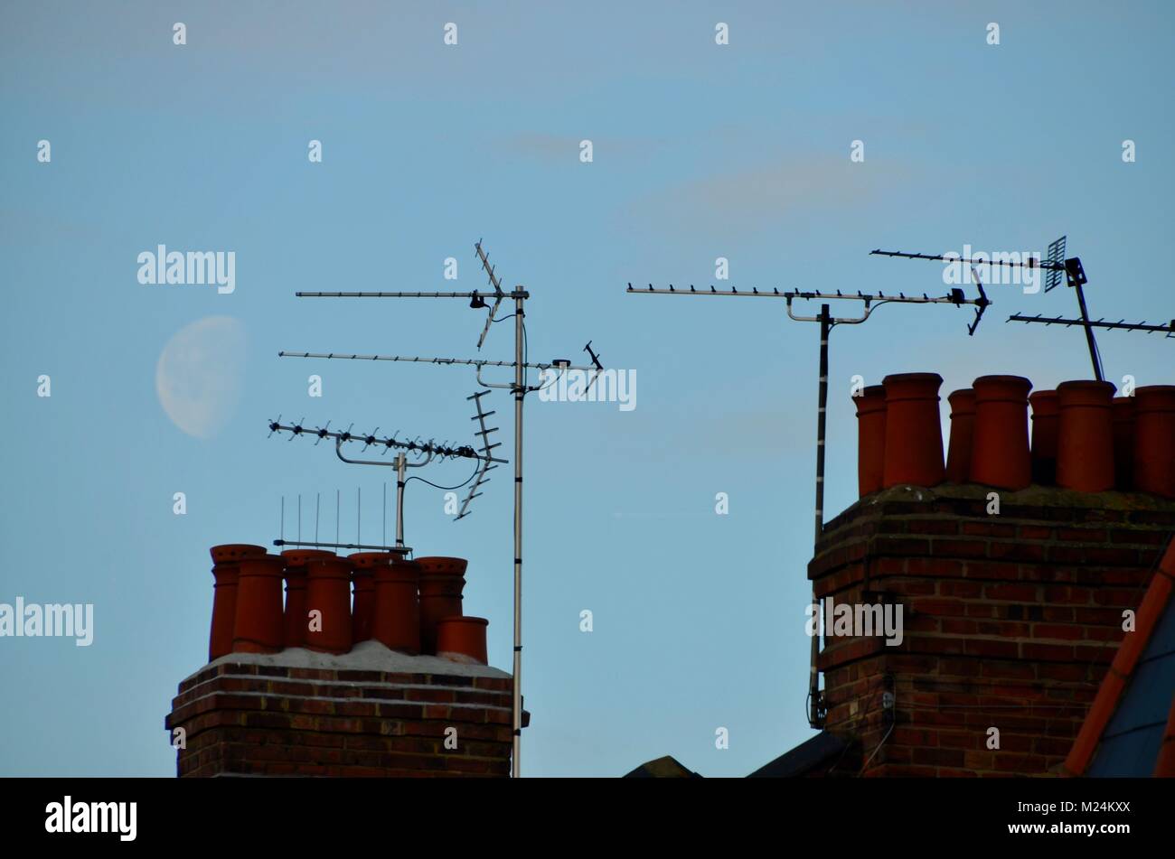 aerials and chimneys on london houses with a large moon behind Stock Photo