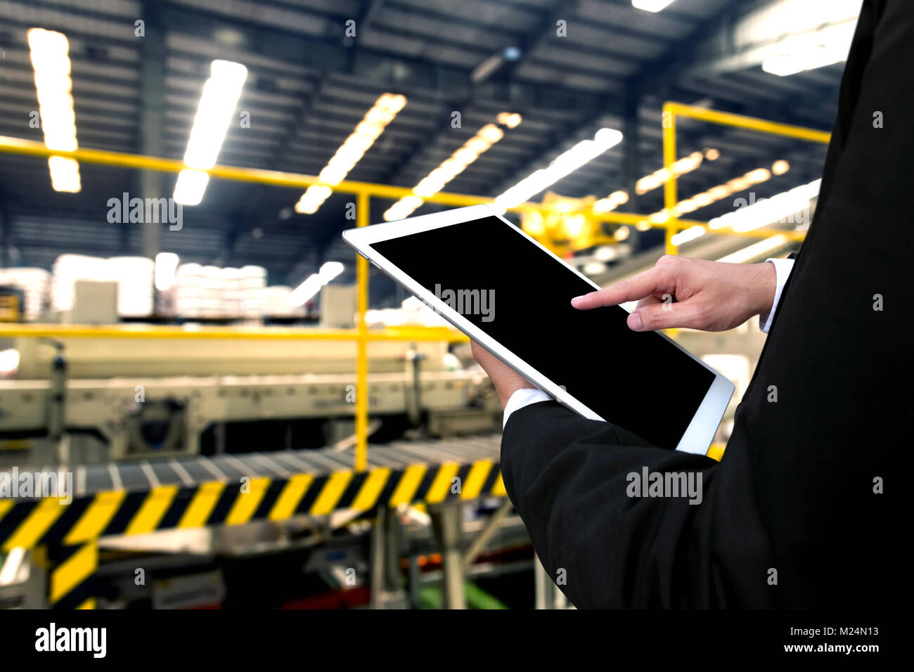 Engineer hand using tablet with machine real time monitoring system software. Automation robot arm , conveyor belt machine  in smart factory industry  Stock Photo