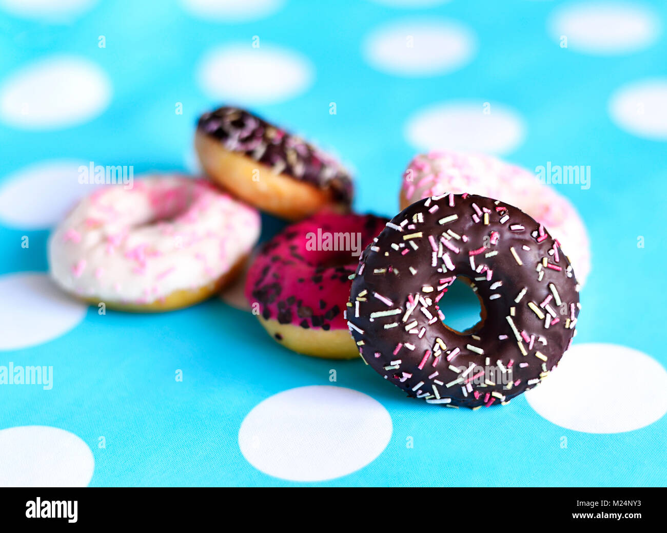 Delicious chocolate donuts with various glaze or icing and sprinkles. fresh donuts on a dotter background, sweet food or unhealthy eating scene. Stock Photo
