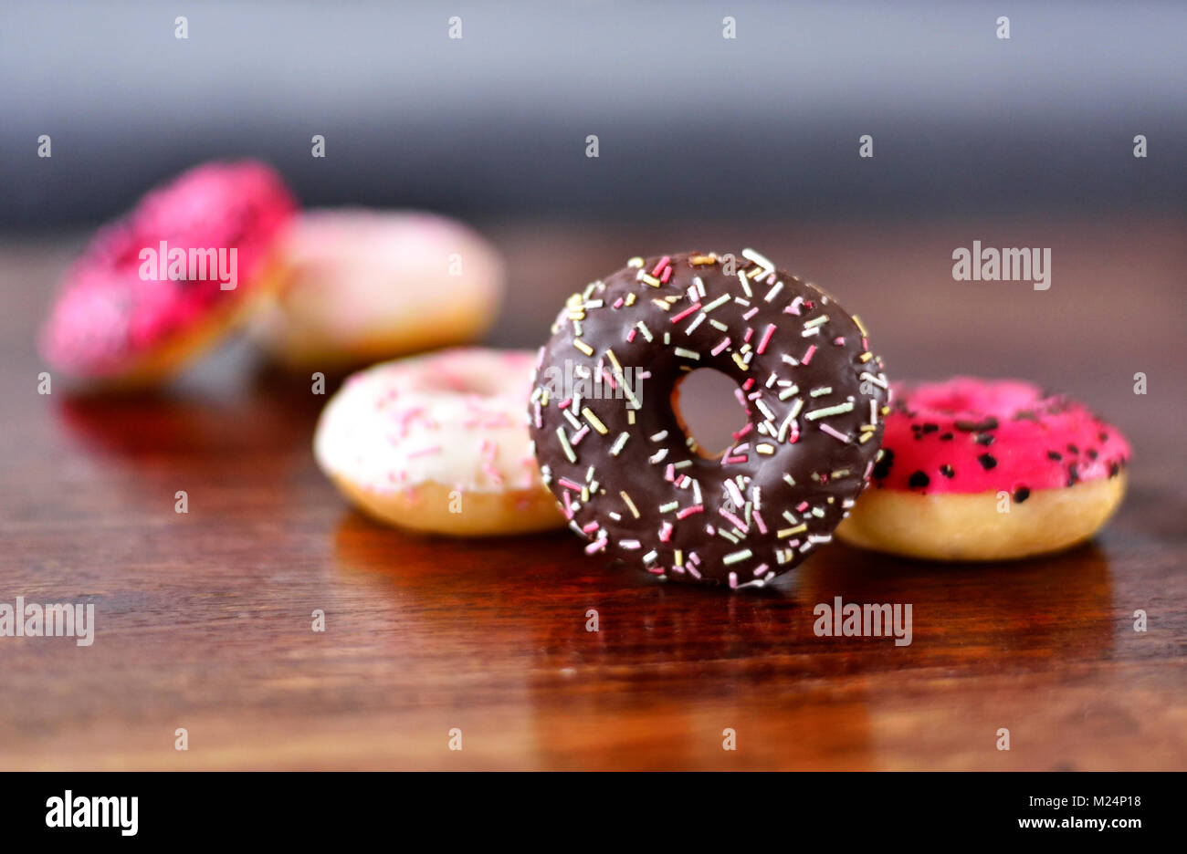 delicious chocolate donuts or fresh donut with glaze or icing and sprinkles. Variation or arrangement of sweet food on a wooden table.Unhealthy eating Stock Photo