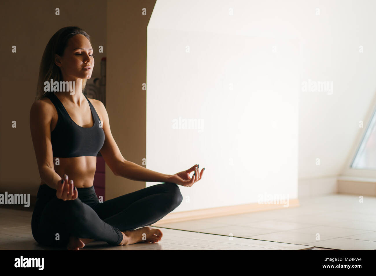 Beautiful woman sitting in lotus pose and meditating at yoga studio ...