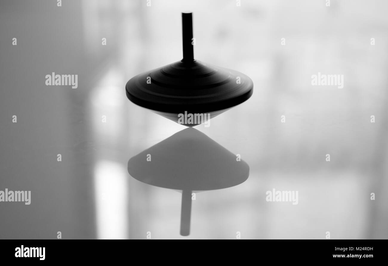 Spinning top in action on a mirror surface Stock Photo