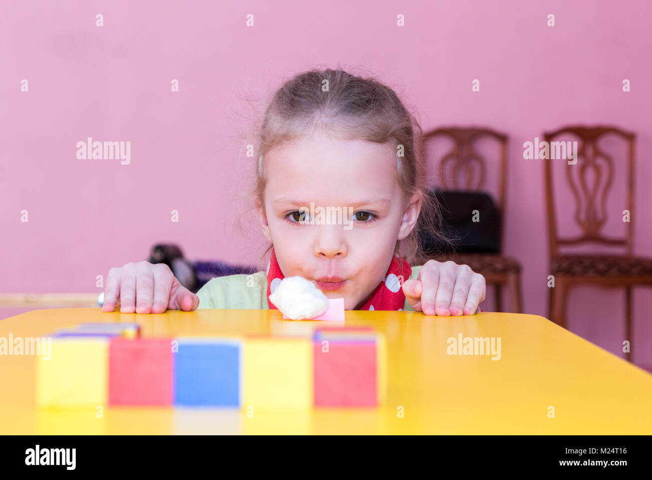 girl blows the cotton ball into the goal Stock Photo