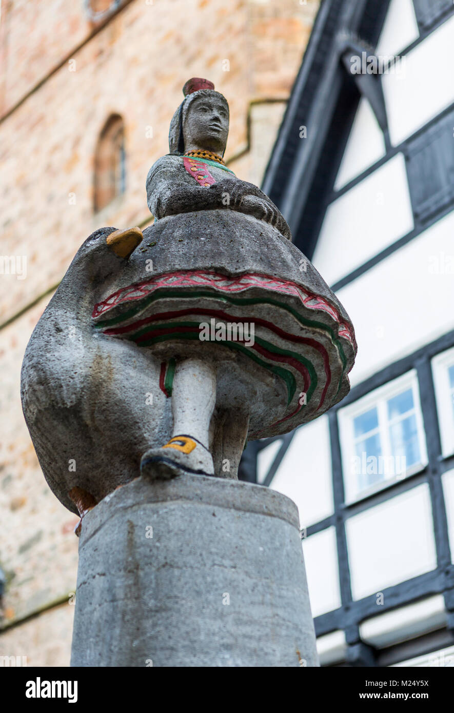 Goose girl or Goose Liesel or Gaenseliesel figure dressed in traditional Hessian costume from Schwalm region, on top of Schwalm Well, Alsfeld, Germany Stock Photo