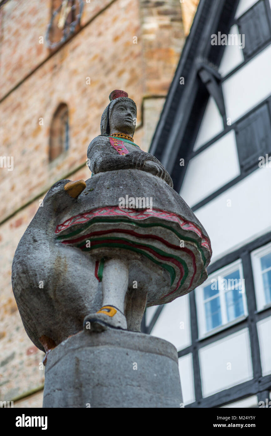 Goose girl or Goose Liesel or Gaenseliesel figure dressed in traditional Hessian costume from Schwalm region, on top of Schwalm Well, Alsfeld, Germany Stock Photo