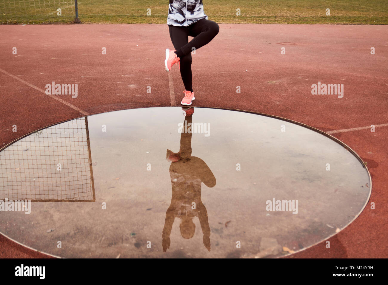 one person exercise, sport clothes, tights, puddle reflection in water, Single-Leg Squat Stock Photo