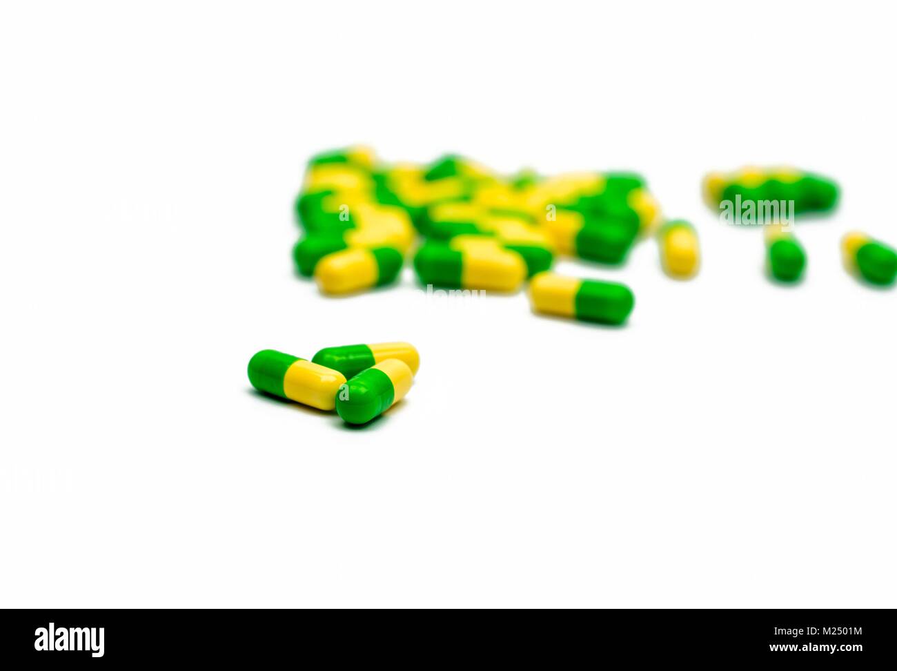 Green, yellow tramadol capsule pills on blurred capsule pills background with copy space. Cancer pain management. Opioid analgesics. Drug abuse in tee Stock Photo