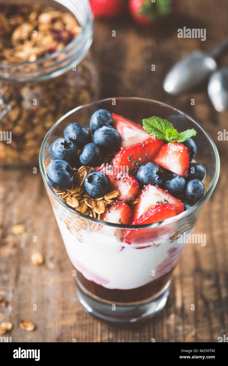 Breakfast yogurt with fresh berries and granola in glass. Selective