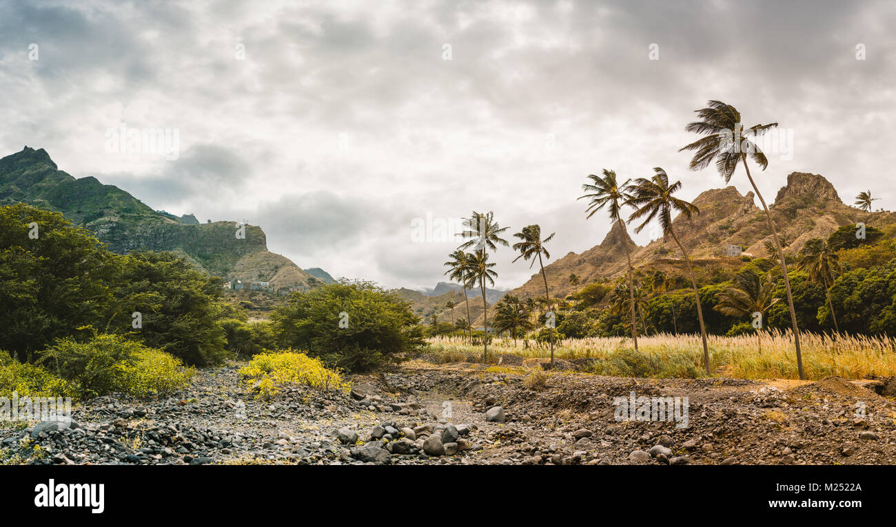 Panorama of dried-up stream surrounded by fertile green valley and rugged cliffs. Santo Antao, Cabo Verde Stock Photo