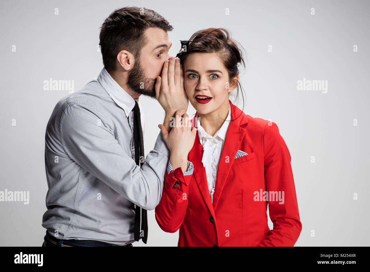 Young man telling gossips to his woman colleague at the office Stock Photo