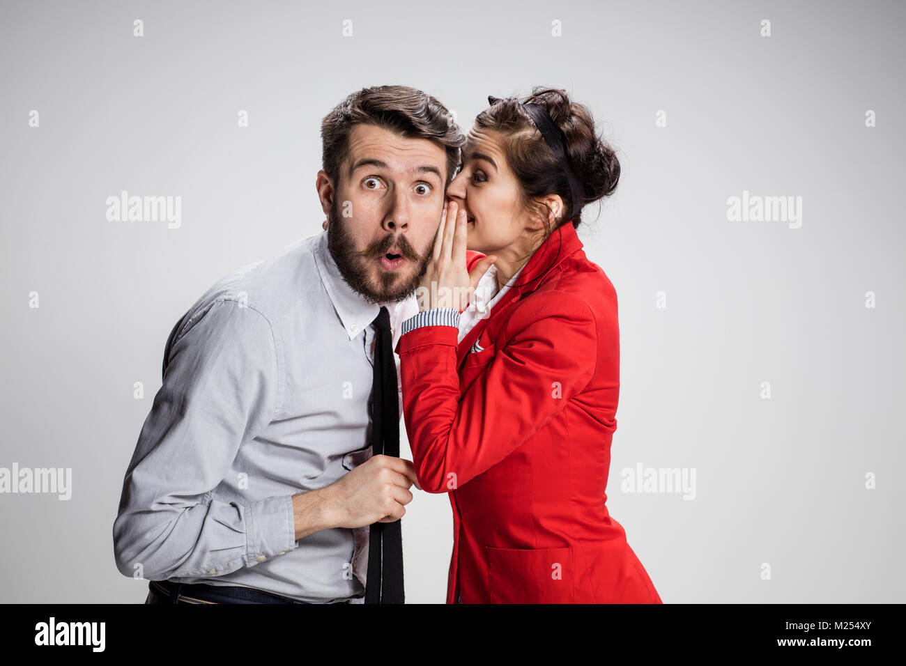 Young man telling gossips to his woman colleague at the office Stock Photo