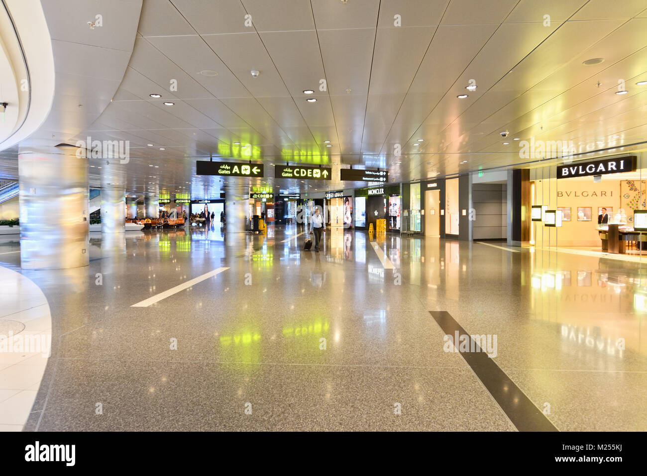 Qatar, Doha, Hamad International Airport. In the transit area, a traveler walks among the premium branded shops within the airport's shopping area. Stock Photo
