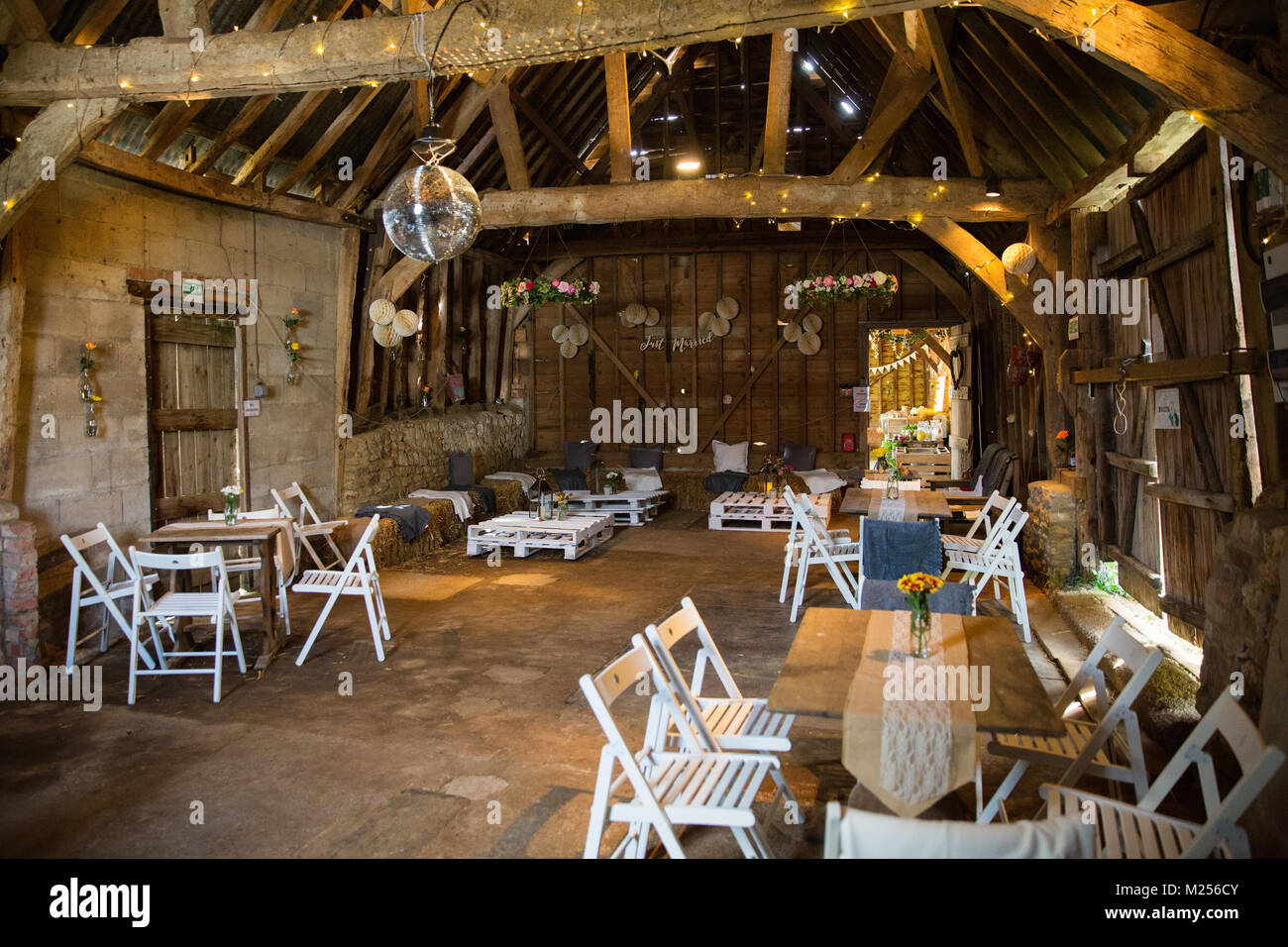 Barn decorated for special occasion with glitter ball, string lights, tables and chairs Stock Photo