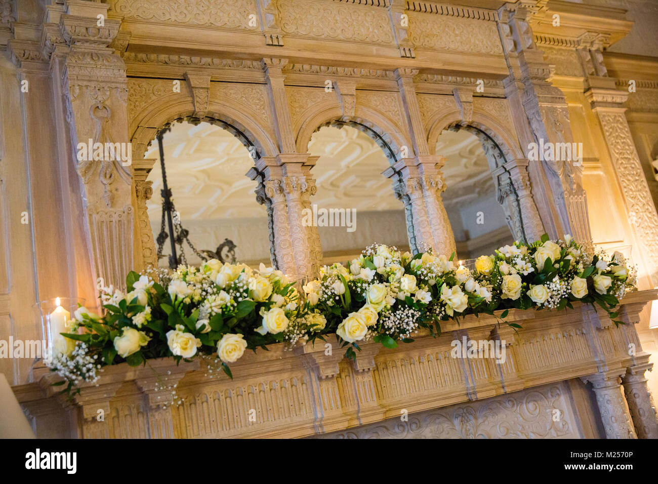 Romantic floral arrangement on ornate mantlepiece with wall mirrors Stock Photo