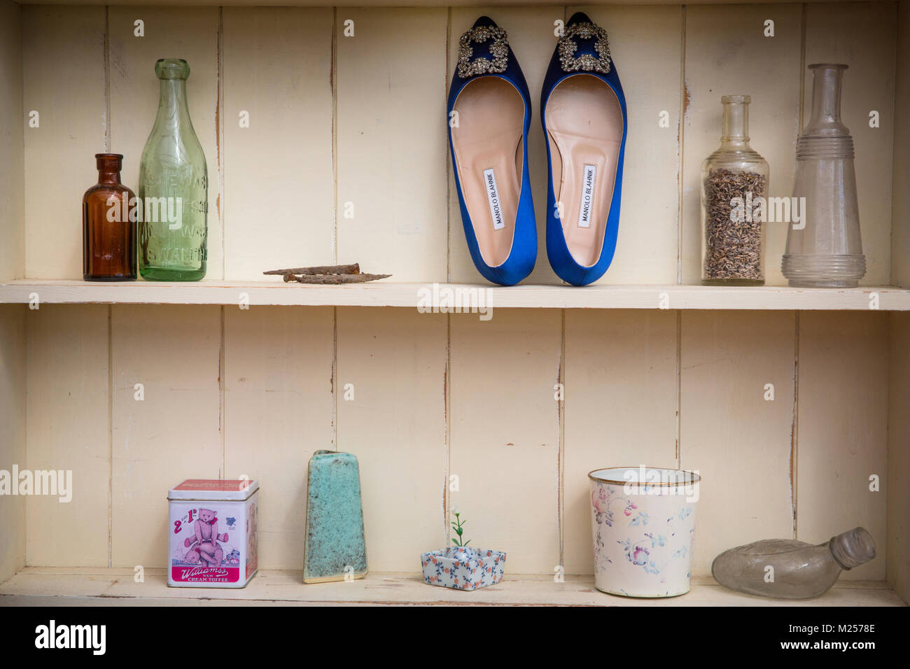 Cream coloured shelves with vintage bottles and ladies shoes, detail Stock Photo