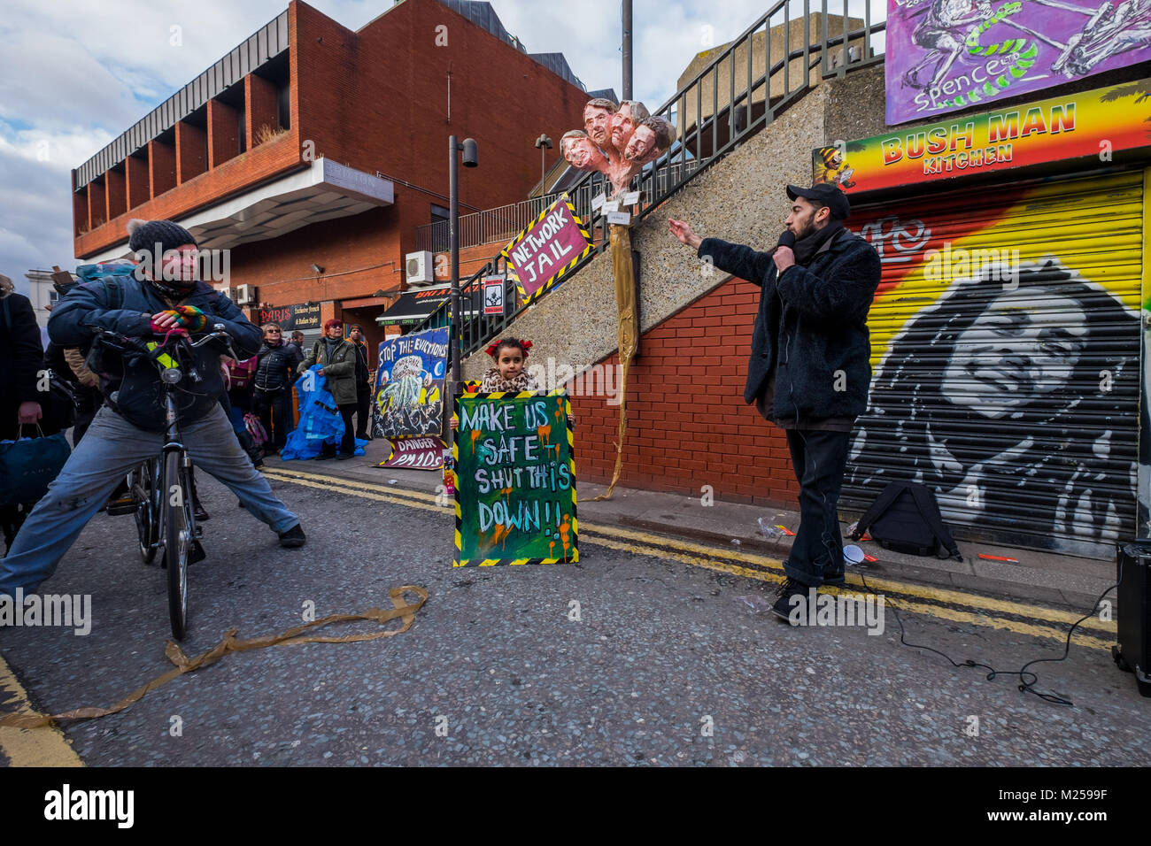 February 5, 2018 - London, UK. 4th February 2018. Artist Andrew Cooper points out his sculpture of theheads of Lambeth Councillors responsible for social cleansing to Aysen Dennis from the Aylesbury Estate. Campaigners mark the third anniversary of the announcement by Network Rail of their plans to redevelop the Brixton Arches with a rally and a three minute silence. The area and its small traders who have been displaced (a few are still fighting to remain) has been described as the 'heart of Brixton'. Stock Photo