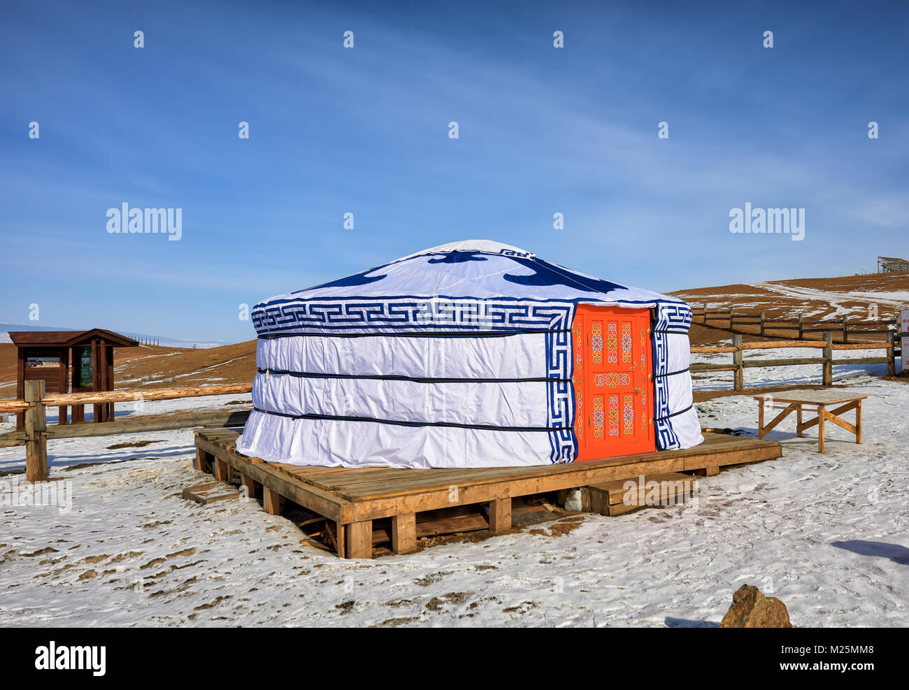 KHUZHIR, IRKUTSK, RUSSIA - March 7, 2017: Buryat yurt is installed on decking floor in steppe by fence. National designs adorn front door and cover Stock Photo