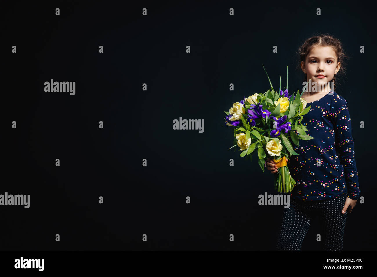 Little girl with bouquet of flowers in her hand. The concept of happiness, people, child, childhood. Studio photo on a black background. mothers Day.  Stock Photo