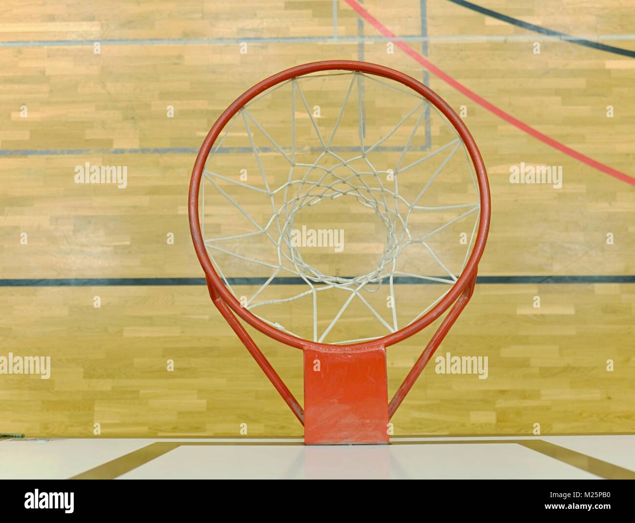 Interior of school gym with basketball board and basket. Safety nets