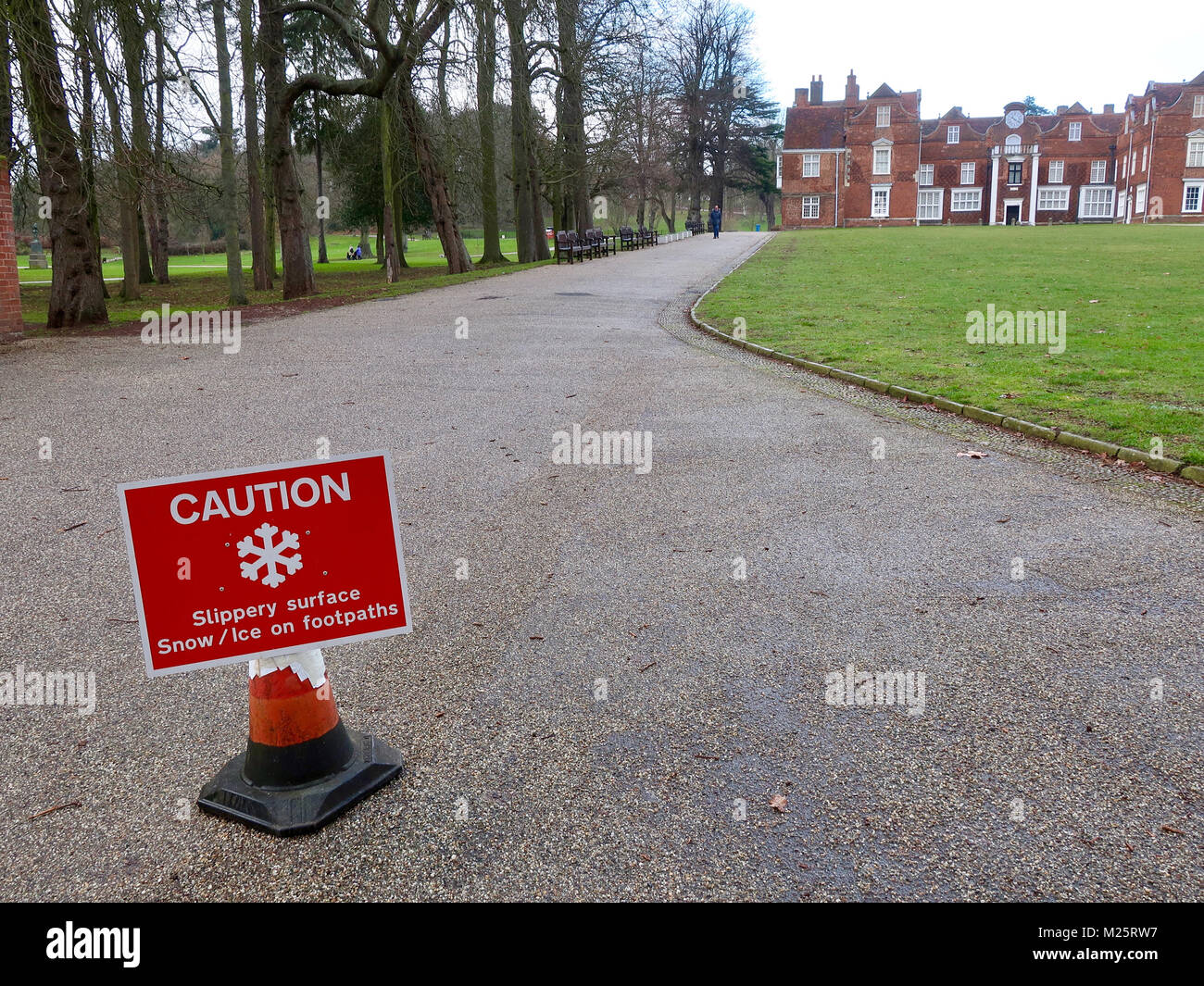 Caution snow / ice slippery surface warning notice out in Christchurch Park after a cold and snowy night. Snow has melted away, risk of ice remains. Stock Photo