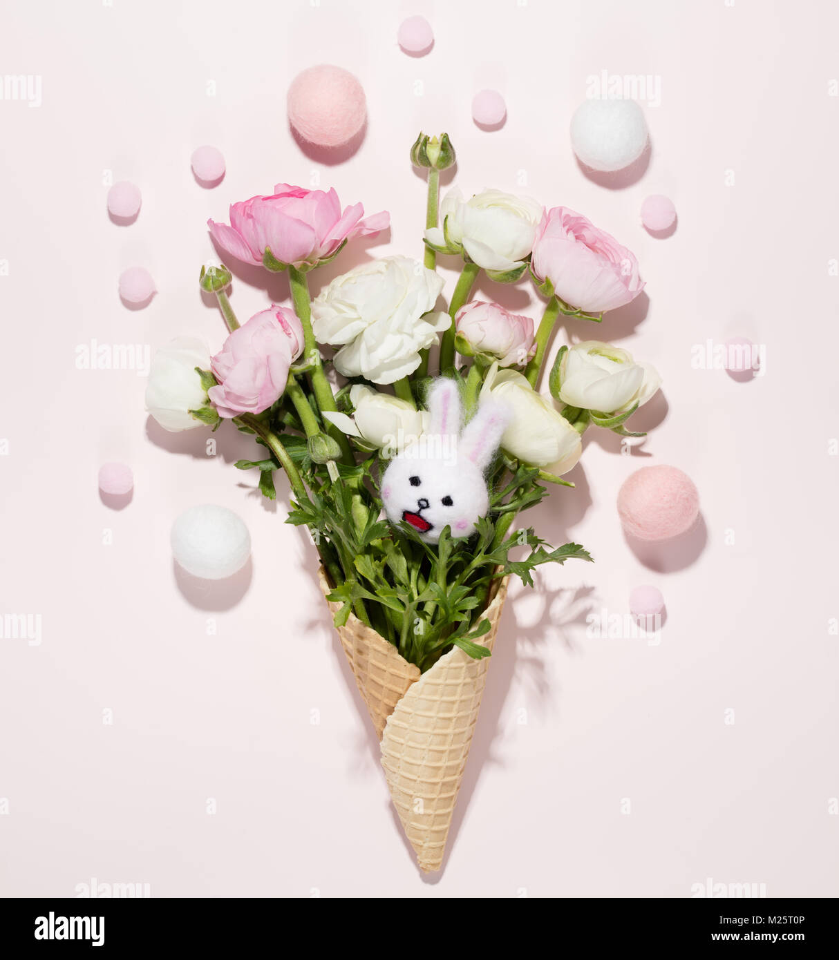 Buttercup flowers in the waffle cone with easter eggs on pink background Stock Photo