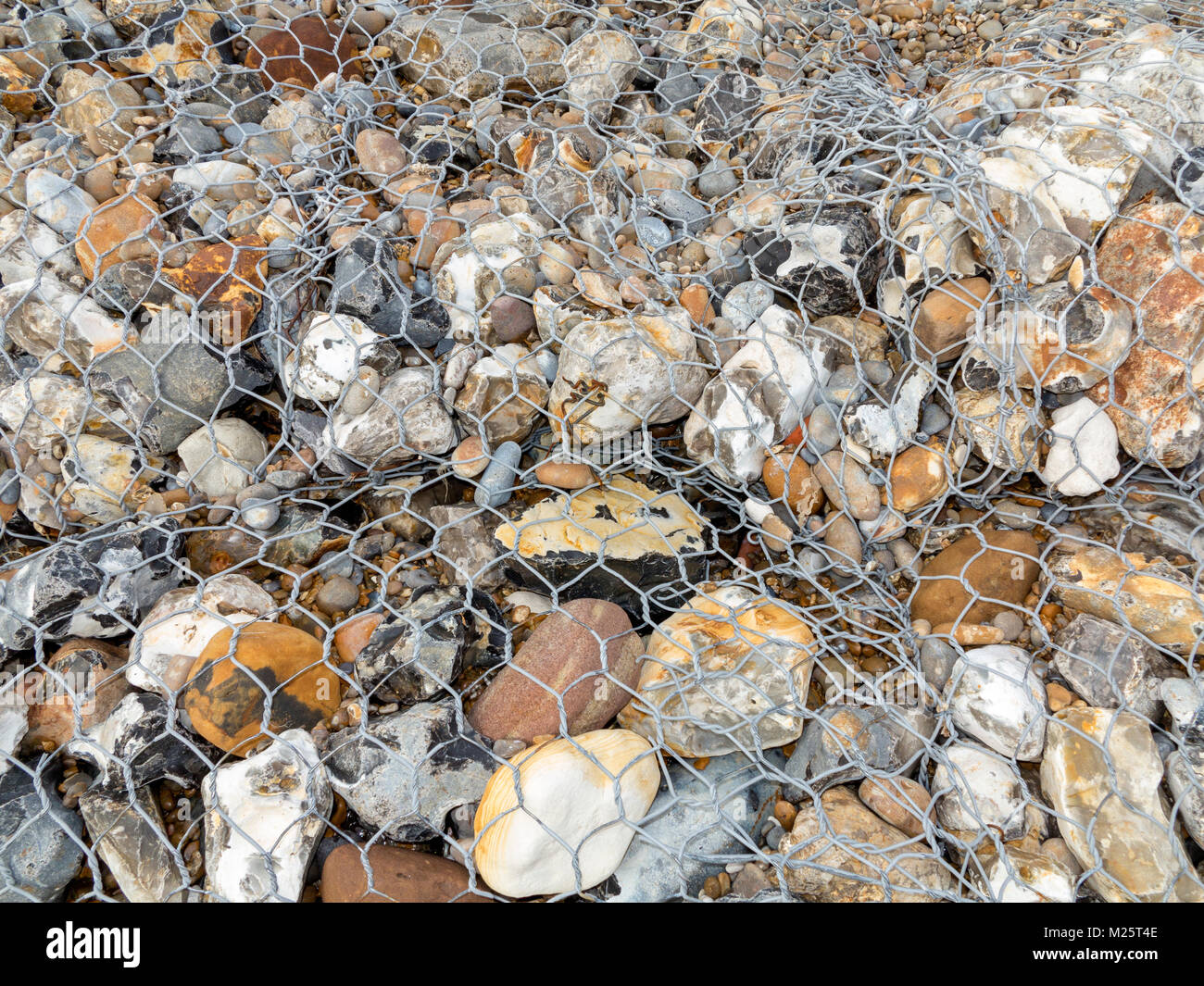 Sea defences made from wire mesh cages containing large beach pebbles Stock Photo