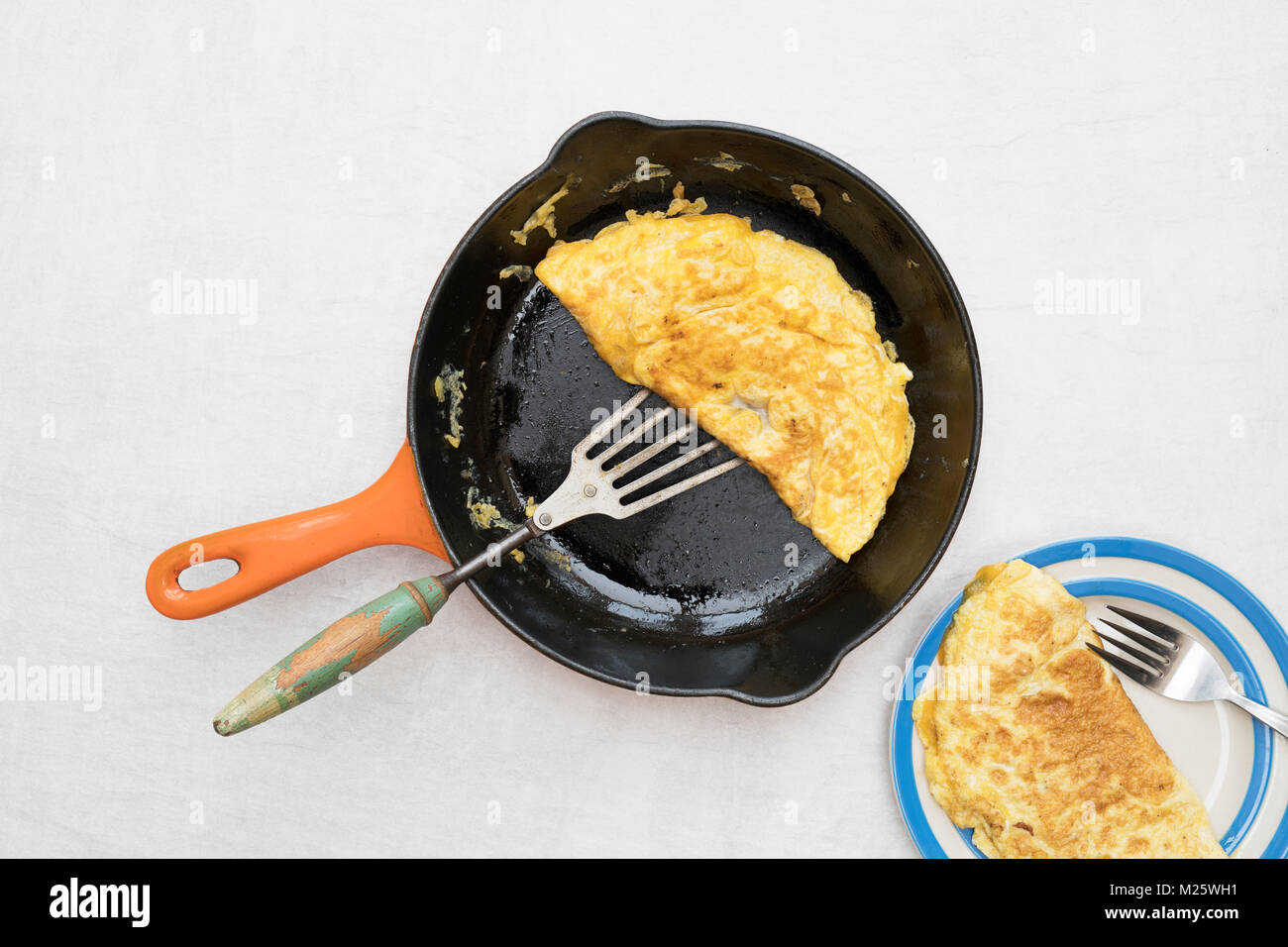 Omelette with melted cheese in a frying pan on a light background Stock Photo