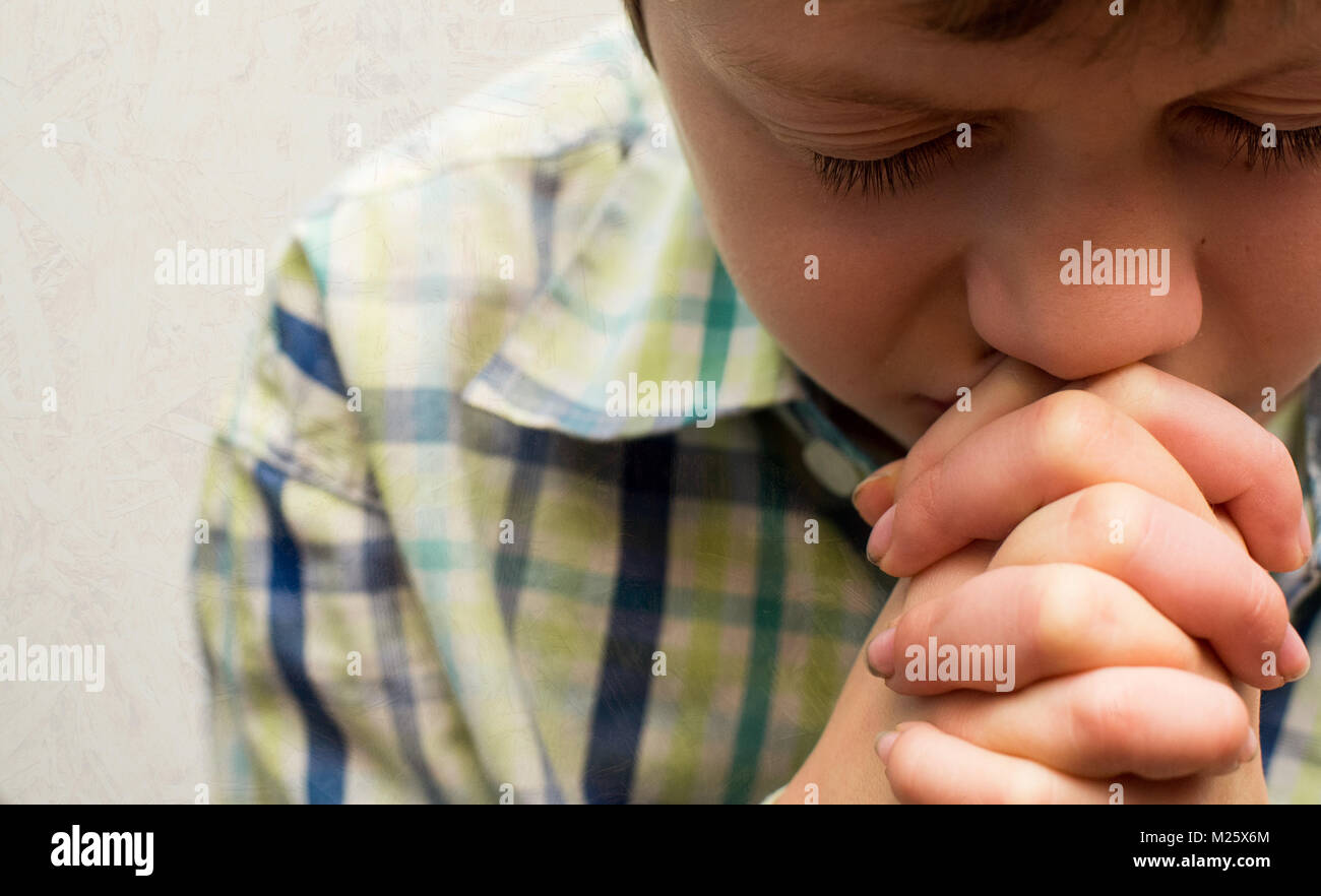 A young boy with his head bowed in prayer Stock Photo