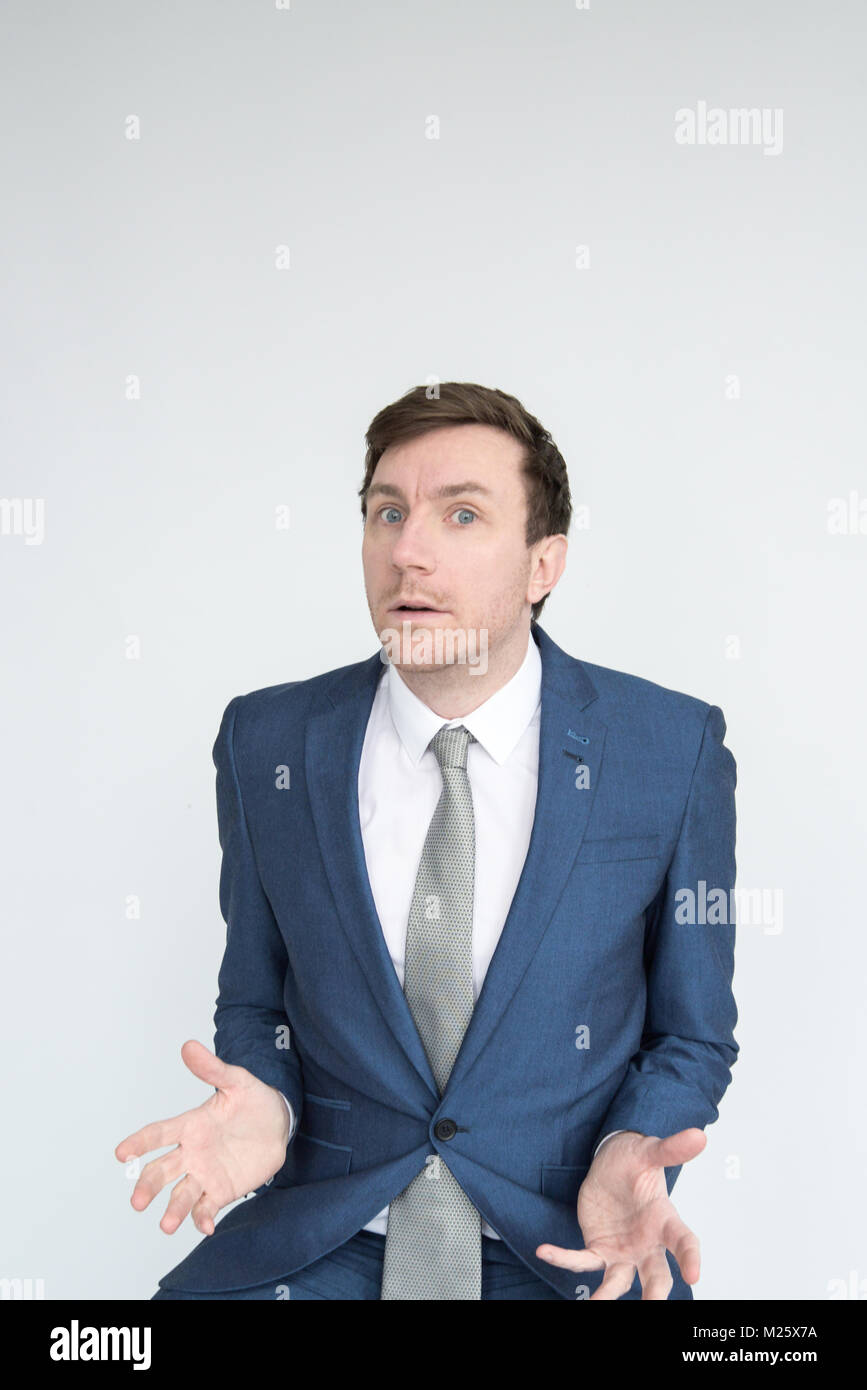 Portrait of a well dressed man in a suit looking shocked and distraught in to camera. Isolated on a white background Stock Photo