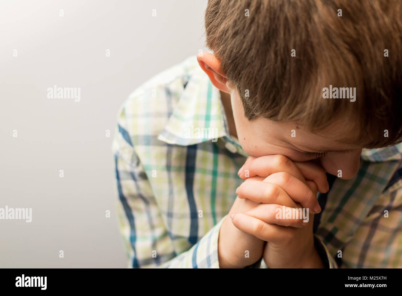 A young boy with his head bowed in prayer Stock Photo