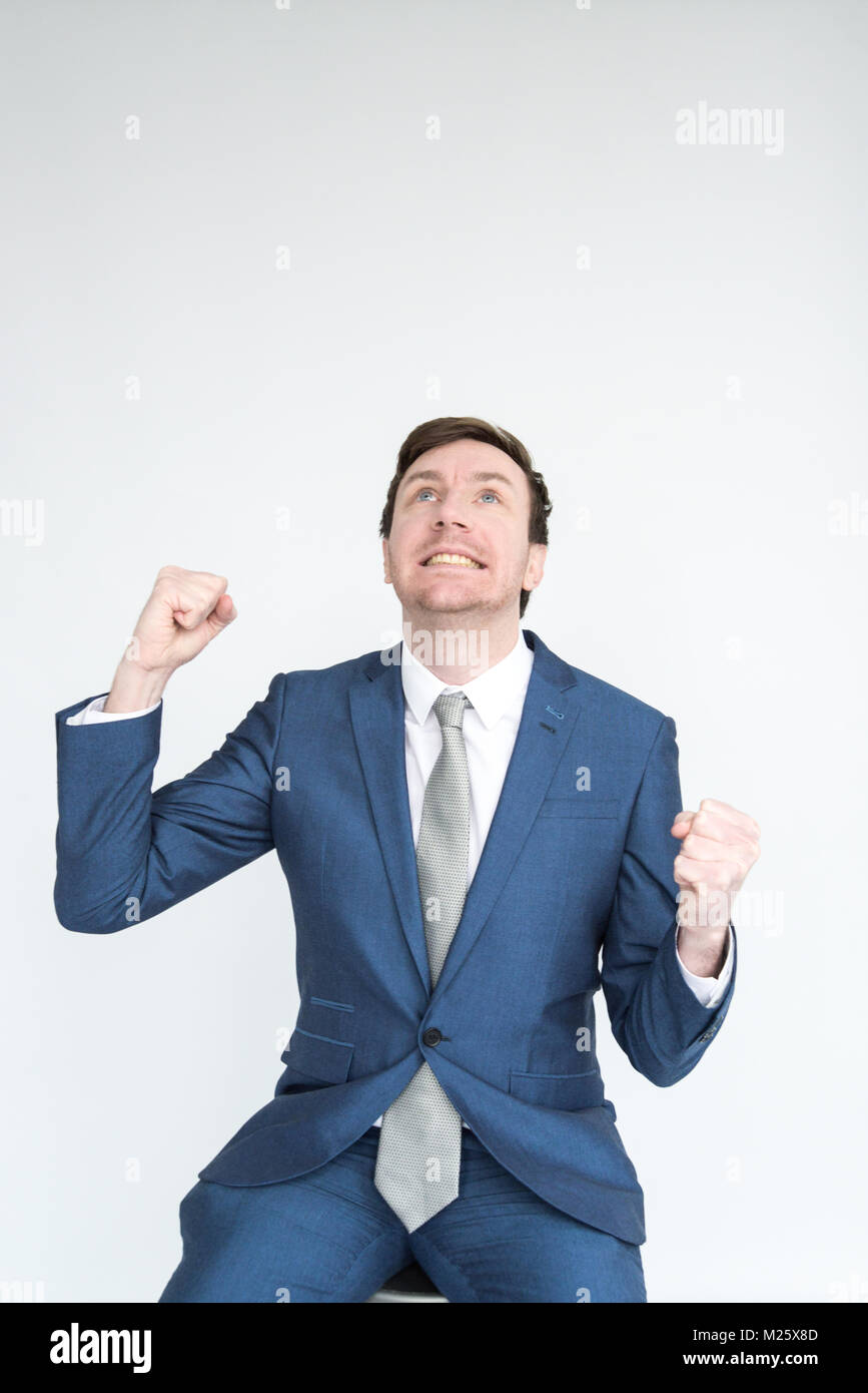 A very excited, well dressed man in a suit punches the air in triumph