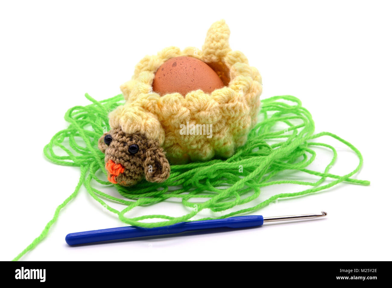 crochet white Easter lamb egg cup made of wool with crochet hook, white isolated background Stock Photo