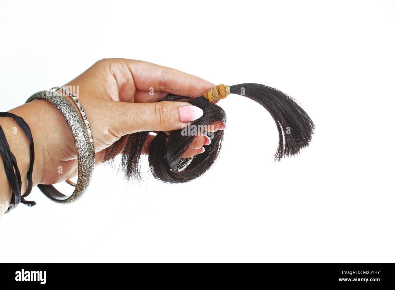 Woman hand holding blach human hair tail on isolated white cutout background. Studio photo with studio lighting easy to use for every concept. Stock Photo