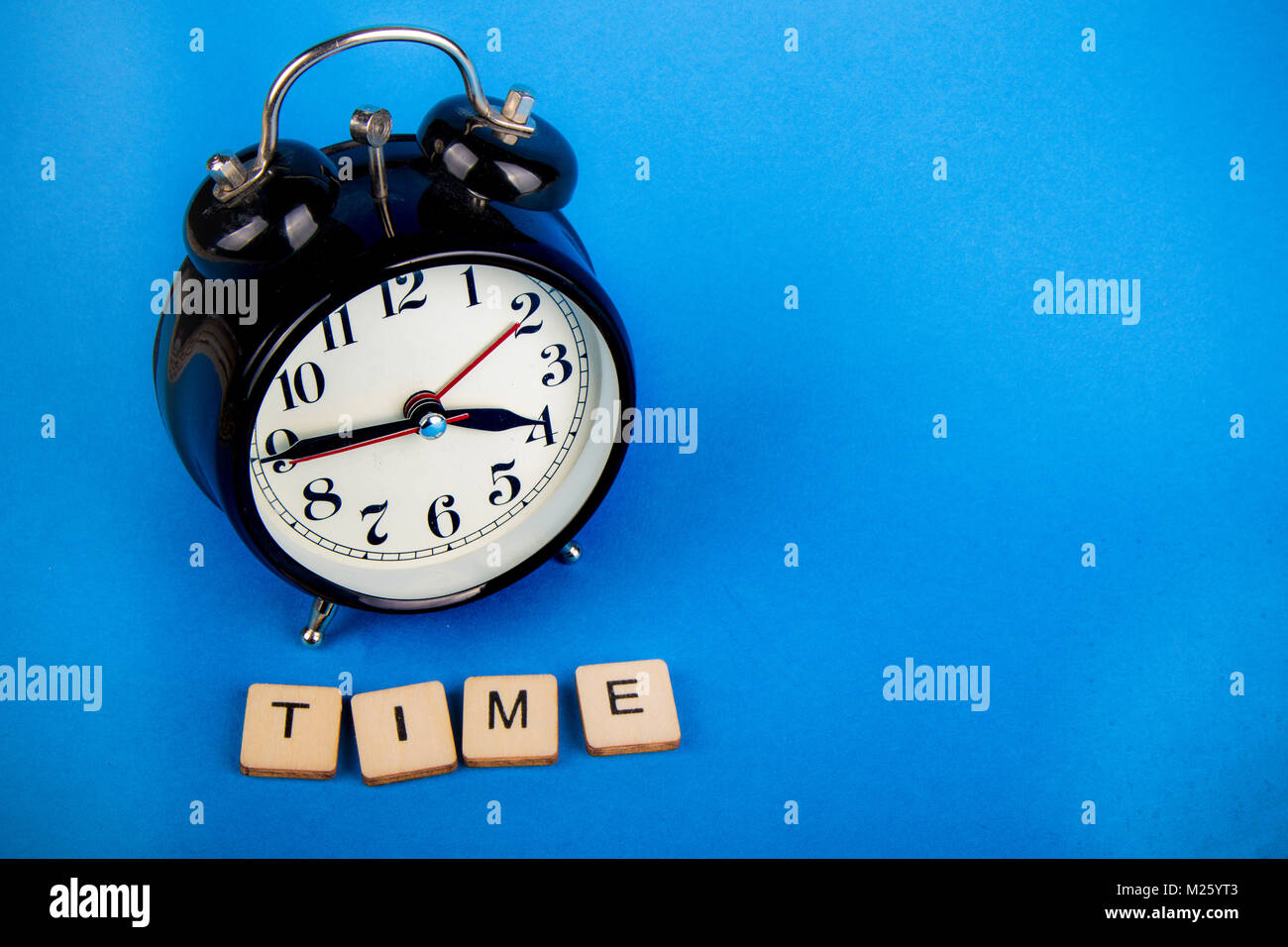 Black alarm clock with a blue background showing time with a sign that