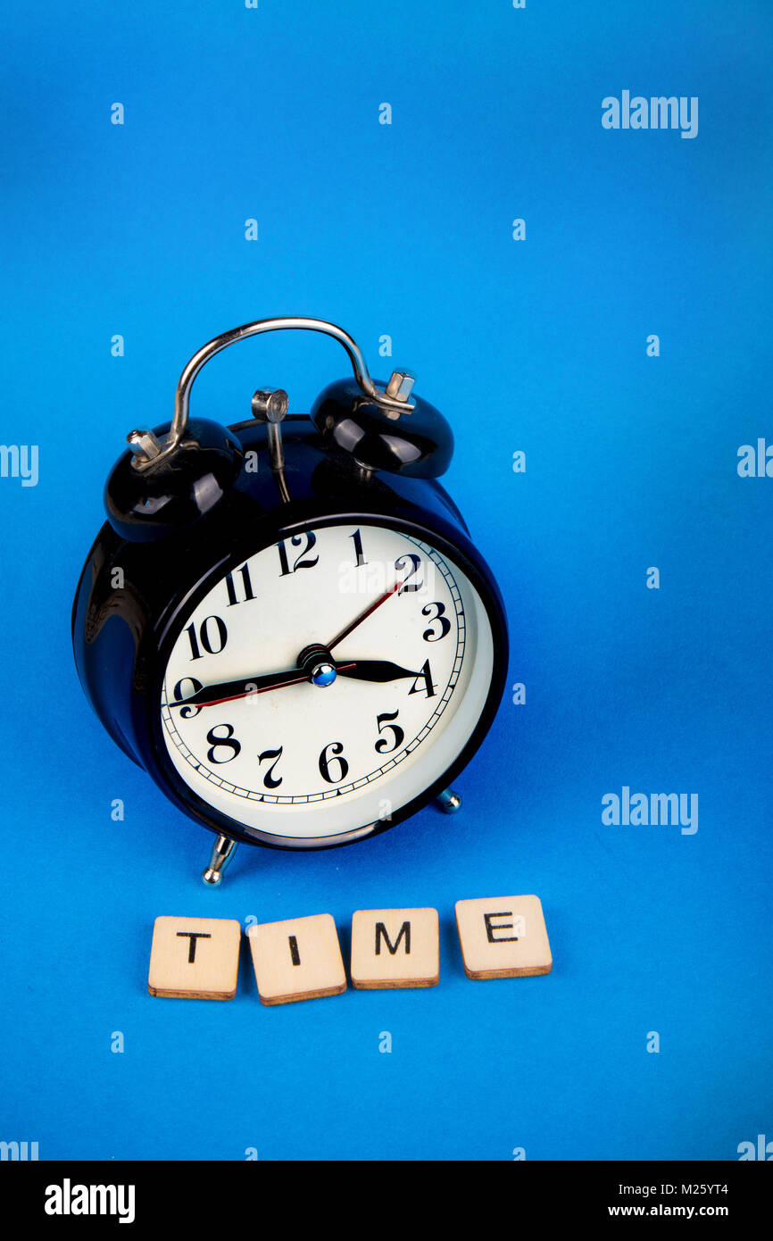 Black alarm clock with a blue background showing time with a sign that