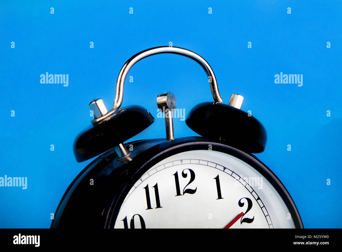 Black alarm clock with a blue background showing time Stock Photo - Alamy