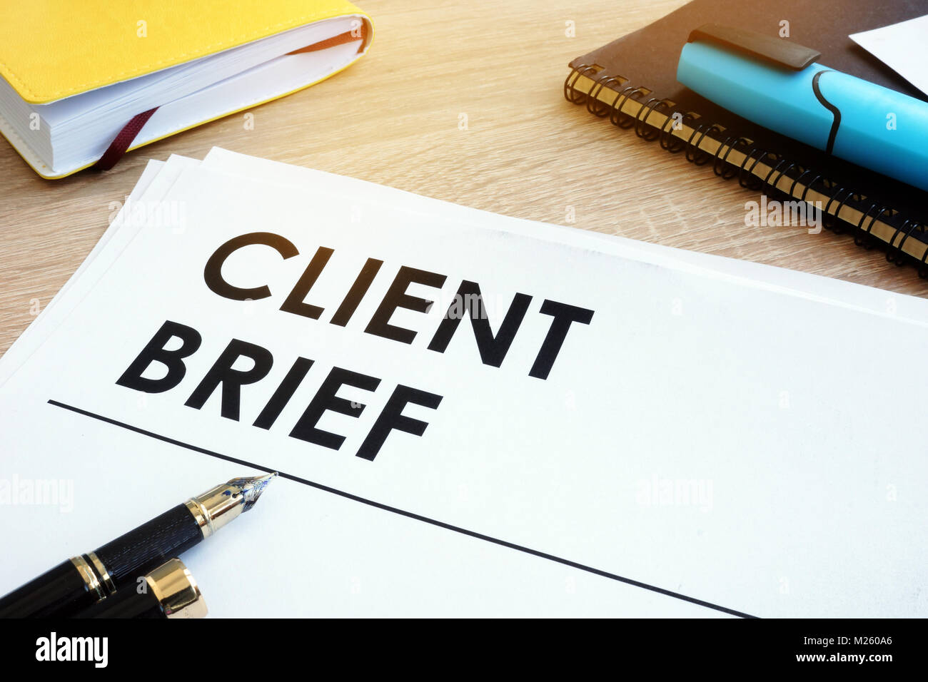 Client brief on a wooden desk with note. Stock Photo