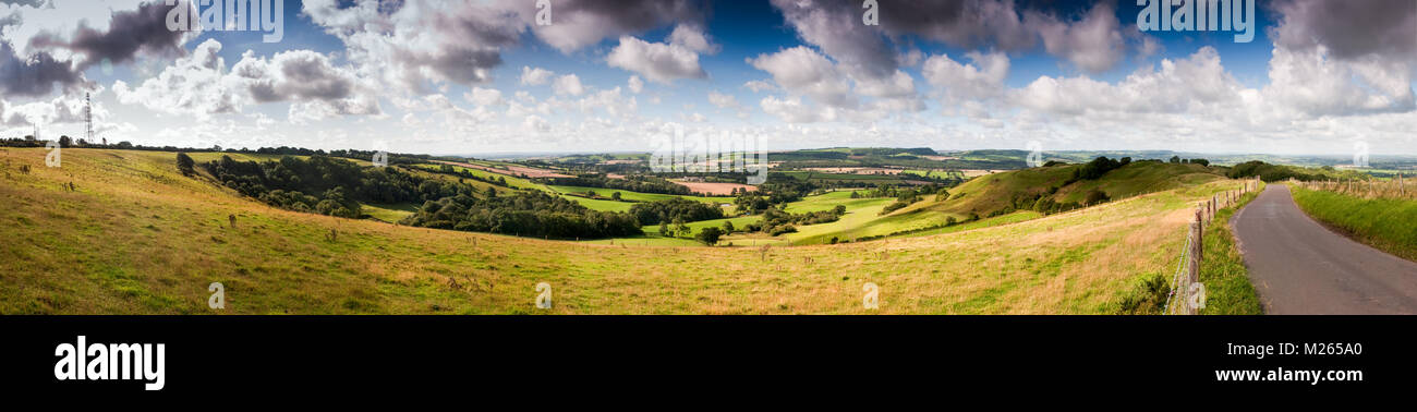 A green patchwork of pasture fields and woodland covers the rolling countryside landscape of England's Dorset Downs hills. Stock Photo