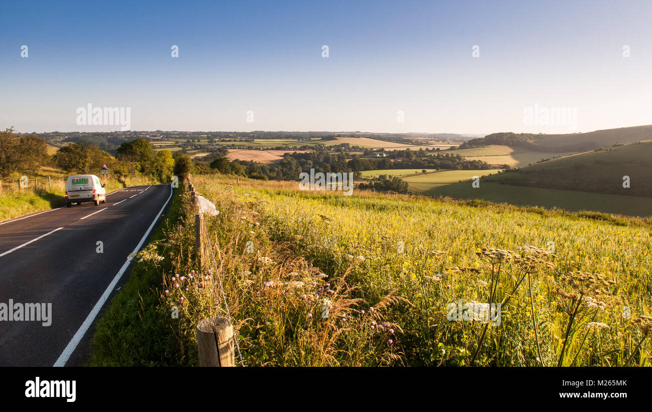 Traffic on the C13 Melbury Abbas road crosses the chalk grassland of Cranborne Chase between Blandford Forum and Shaftesbury in Dorset. Stock Photo