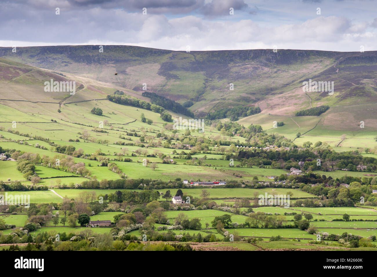 The moorland plateau of Kinder Scout rises above the lush pasture fields of Edale valley in Derbyshire, in England's Peak District National Park. Stock Photo