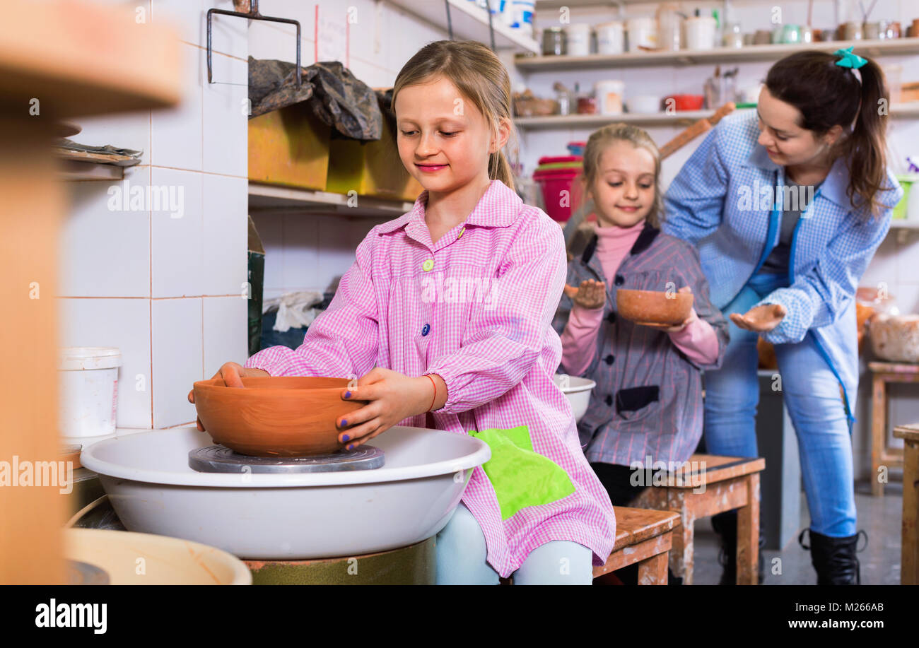 Happy cheerful schoolgirls learning from teacher to make ceramics during arts and crafts class Stock Photo