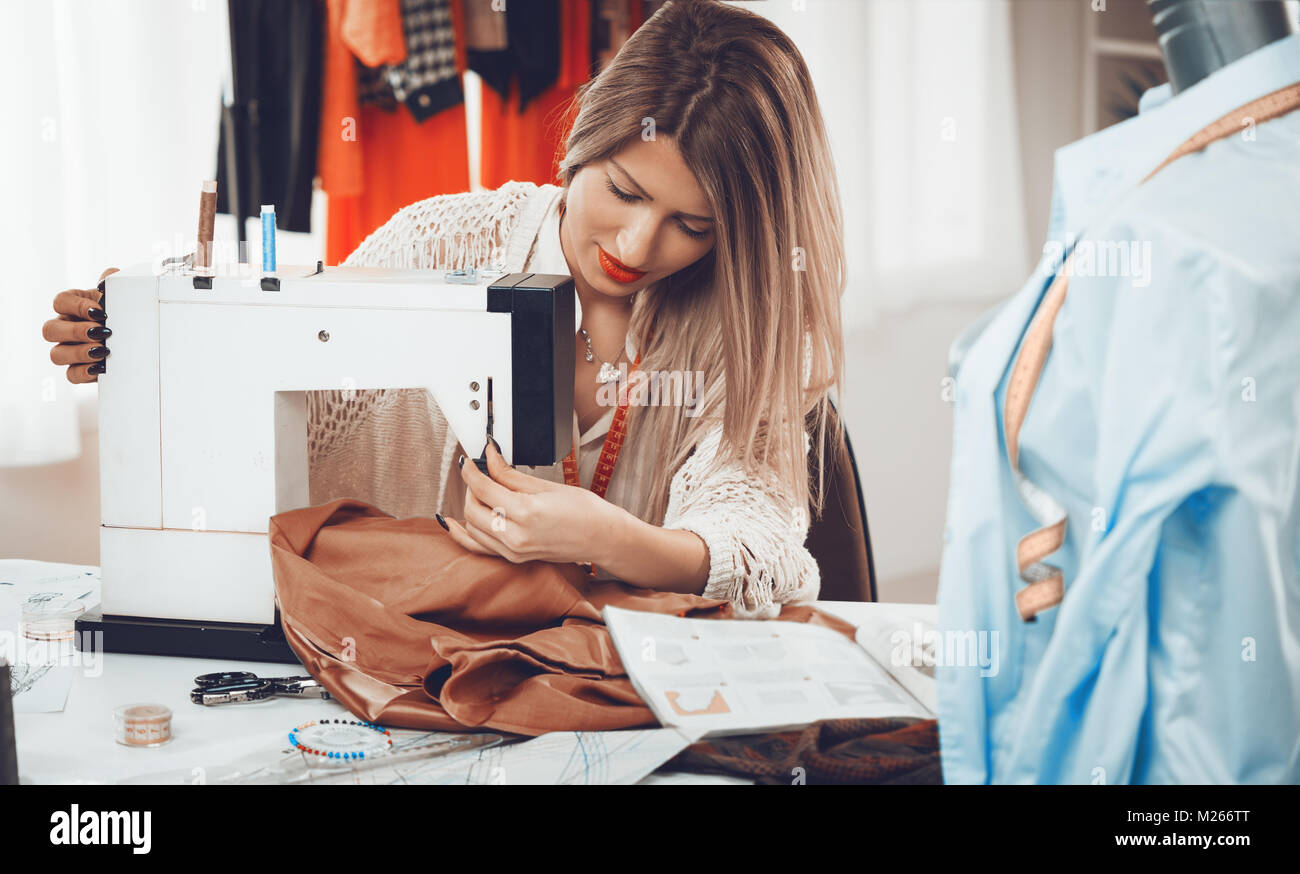 Young beautiful girl sew with a sewing machine. In the background you