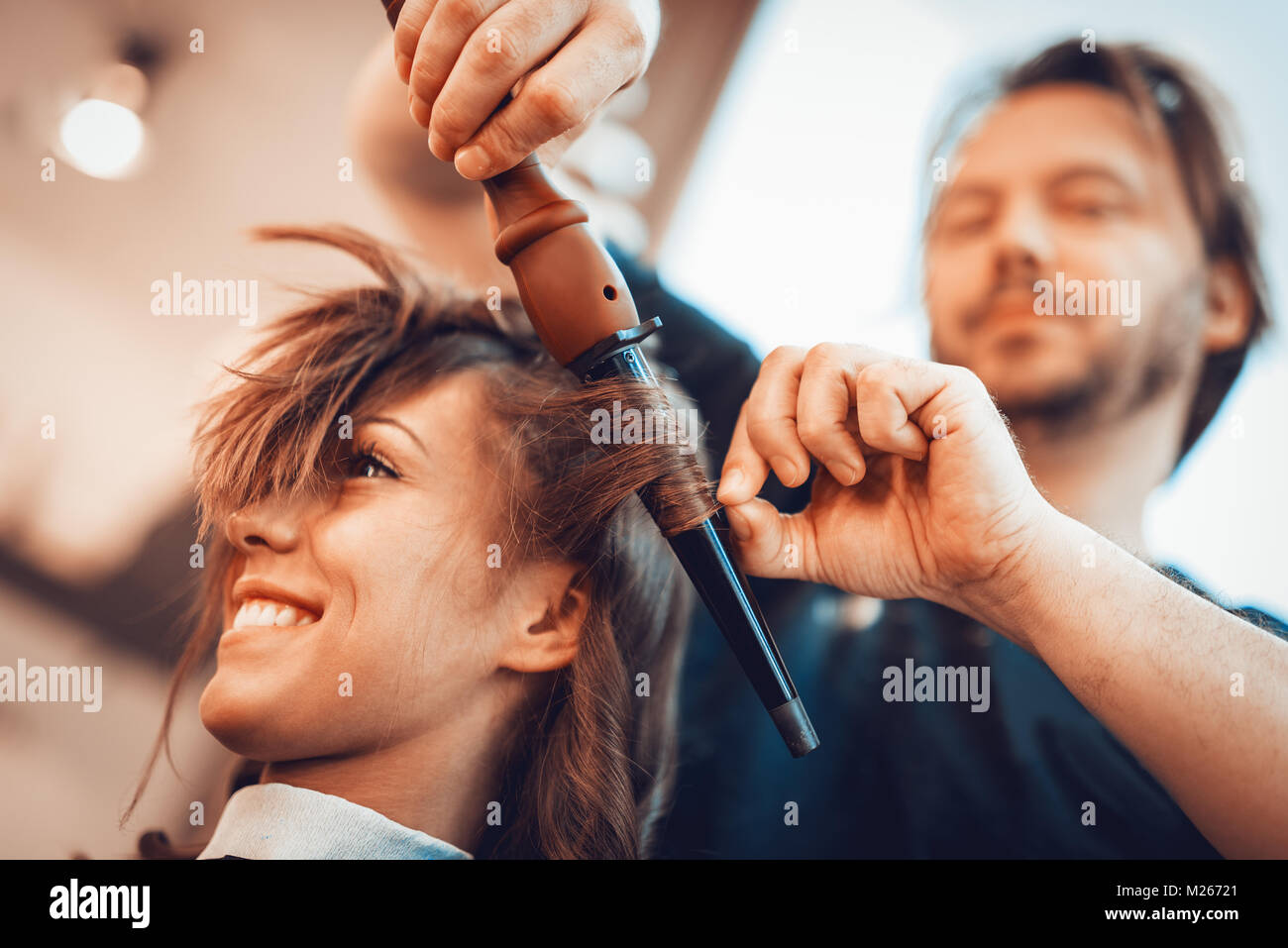 Close Up Of A Male Hairdresser Making Curls At Long Brown Hair