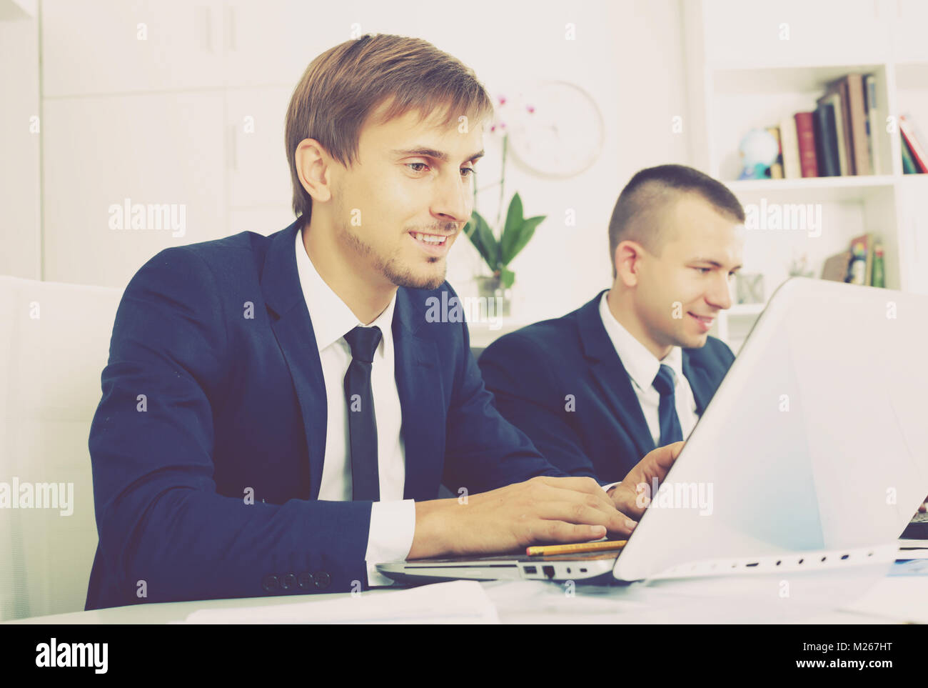 cheerful young man manager sitting with colleagues and working on ...