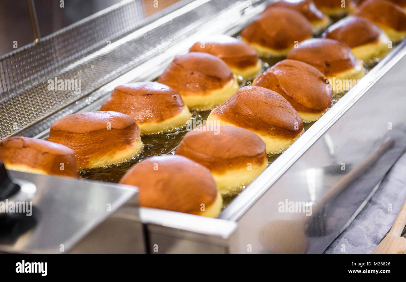 Making homemade jam doughnuts in a professional restaurant buffet kitchen. Deep frying doughnuts