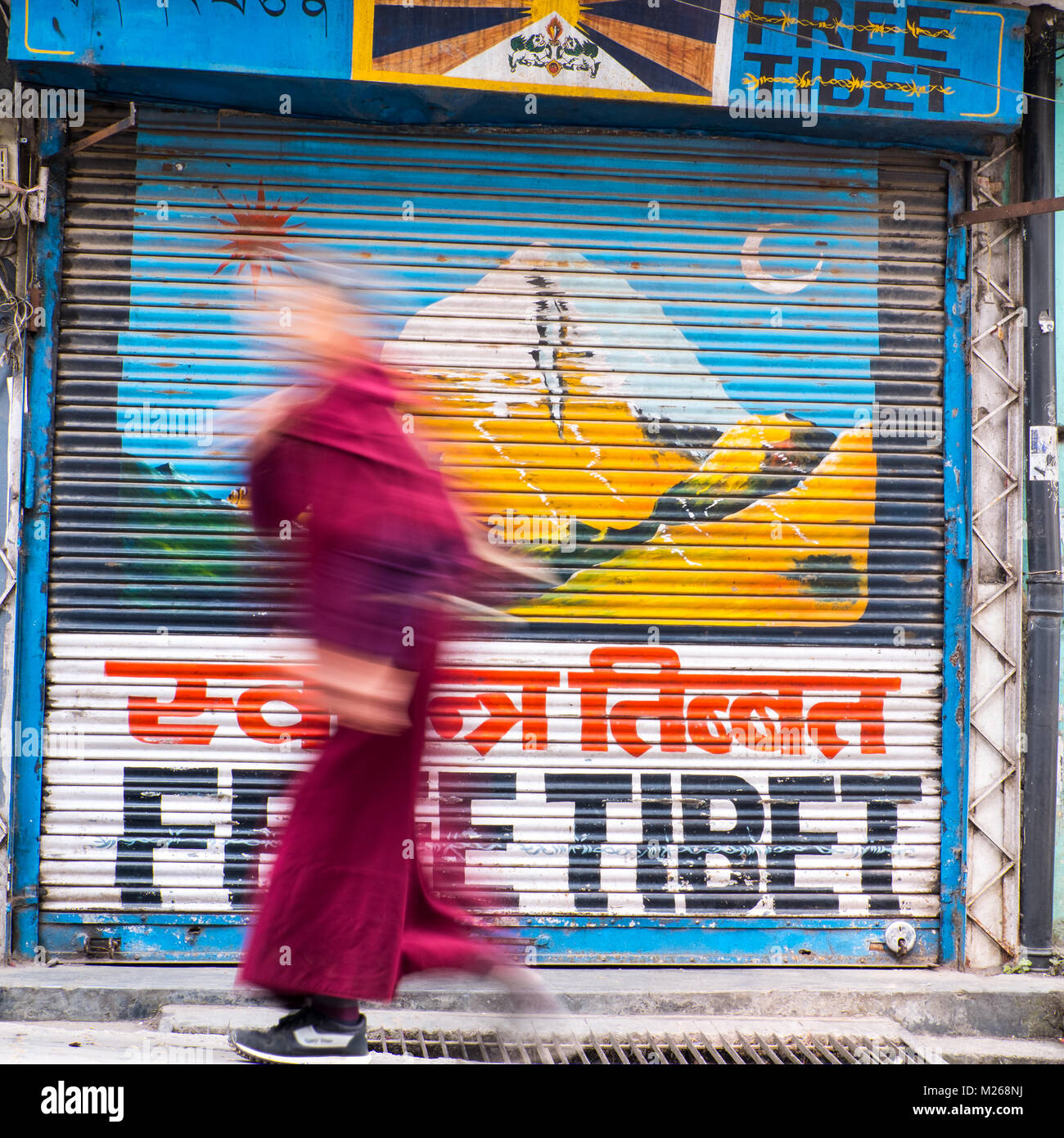 A Buddhist monk passes a 'FREE TIBET' mural in Daramshala,India Stock Photo