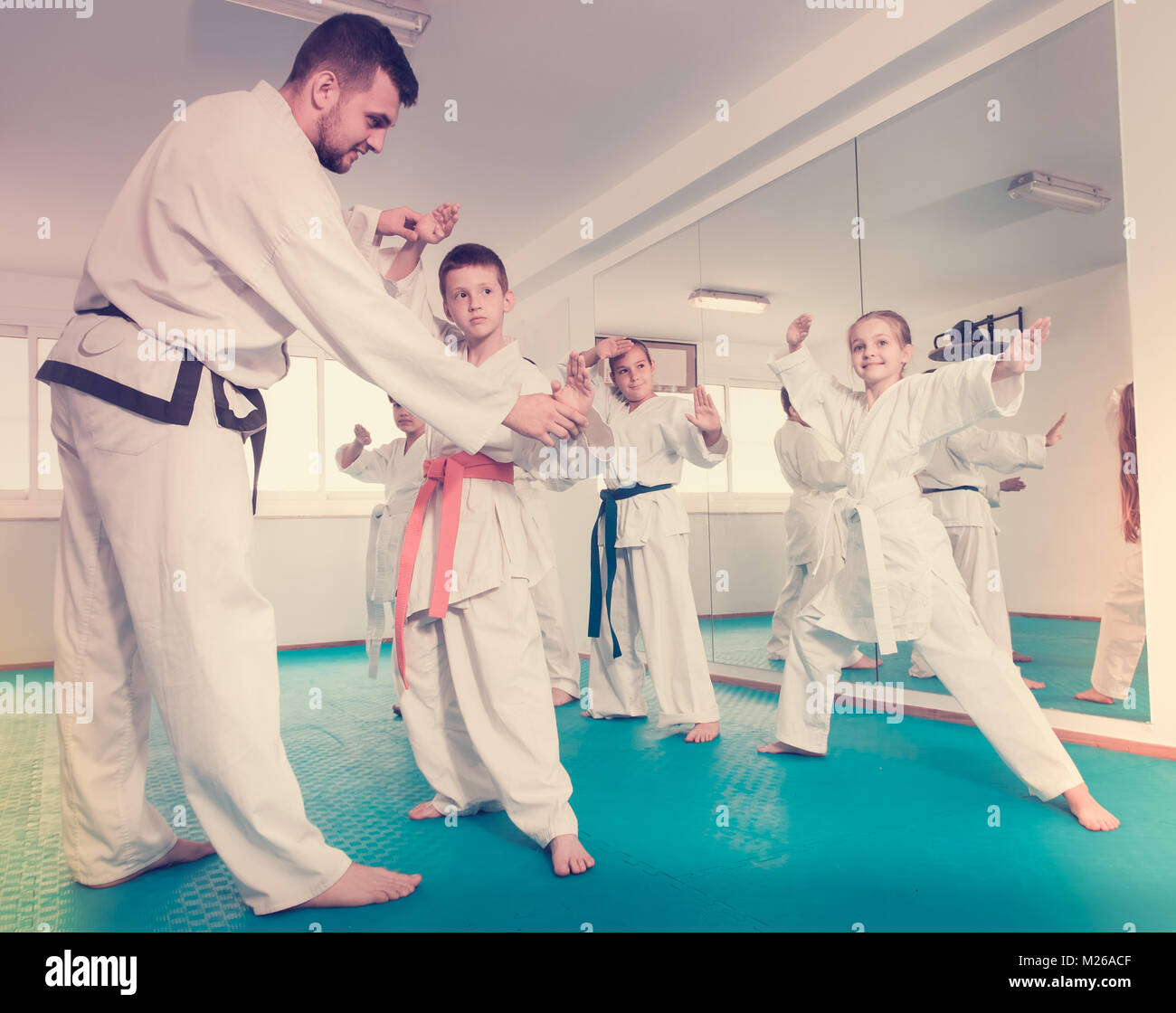 Children training with coach during karate class and trying karate moves Stock Photo