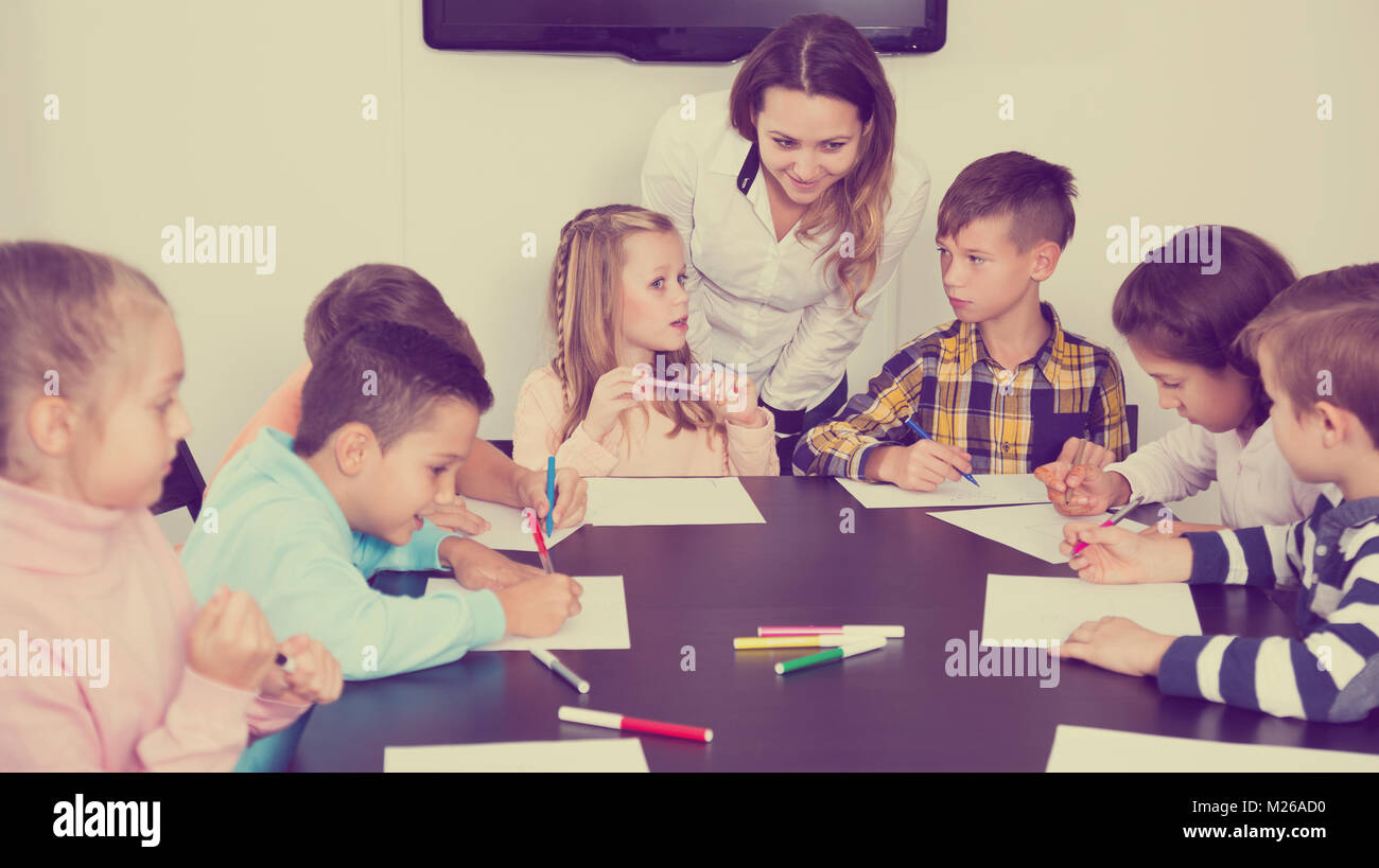 Smiling little boys and girls with teacher drawing in classroom Stock ...