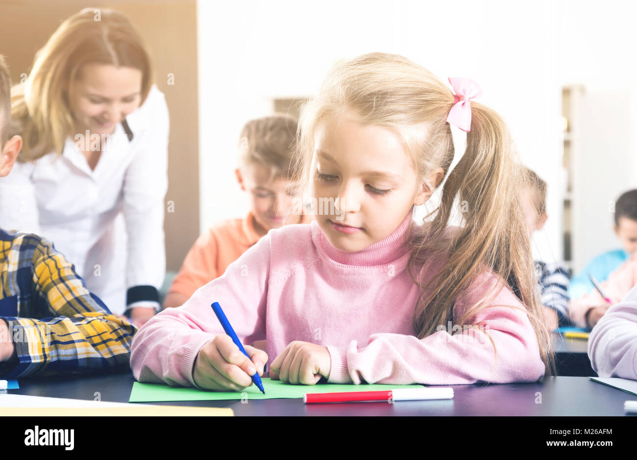 Female teacher and elementary age children drawing at classroom Stock ...