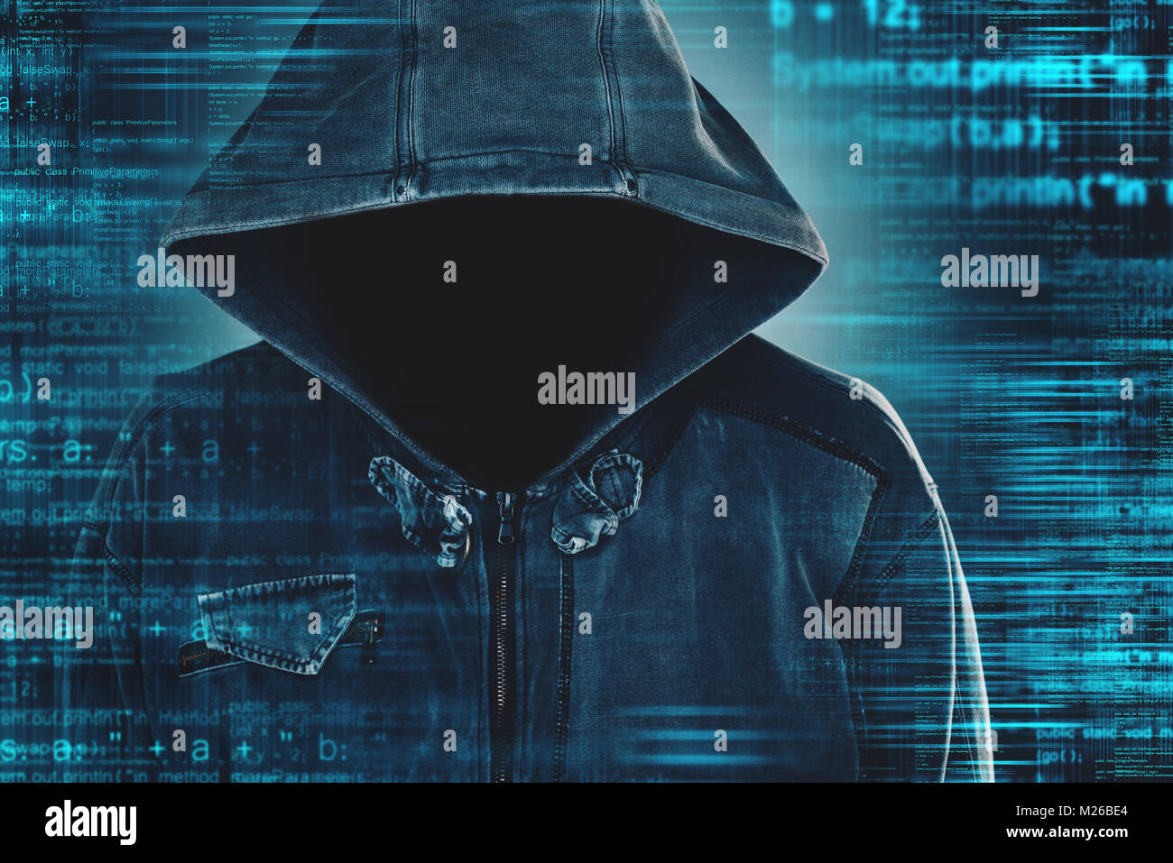 Cybersecurity, computer hacker with hoodie and obscured face, computer code overlaying image Stock Photo